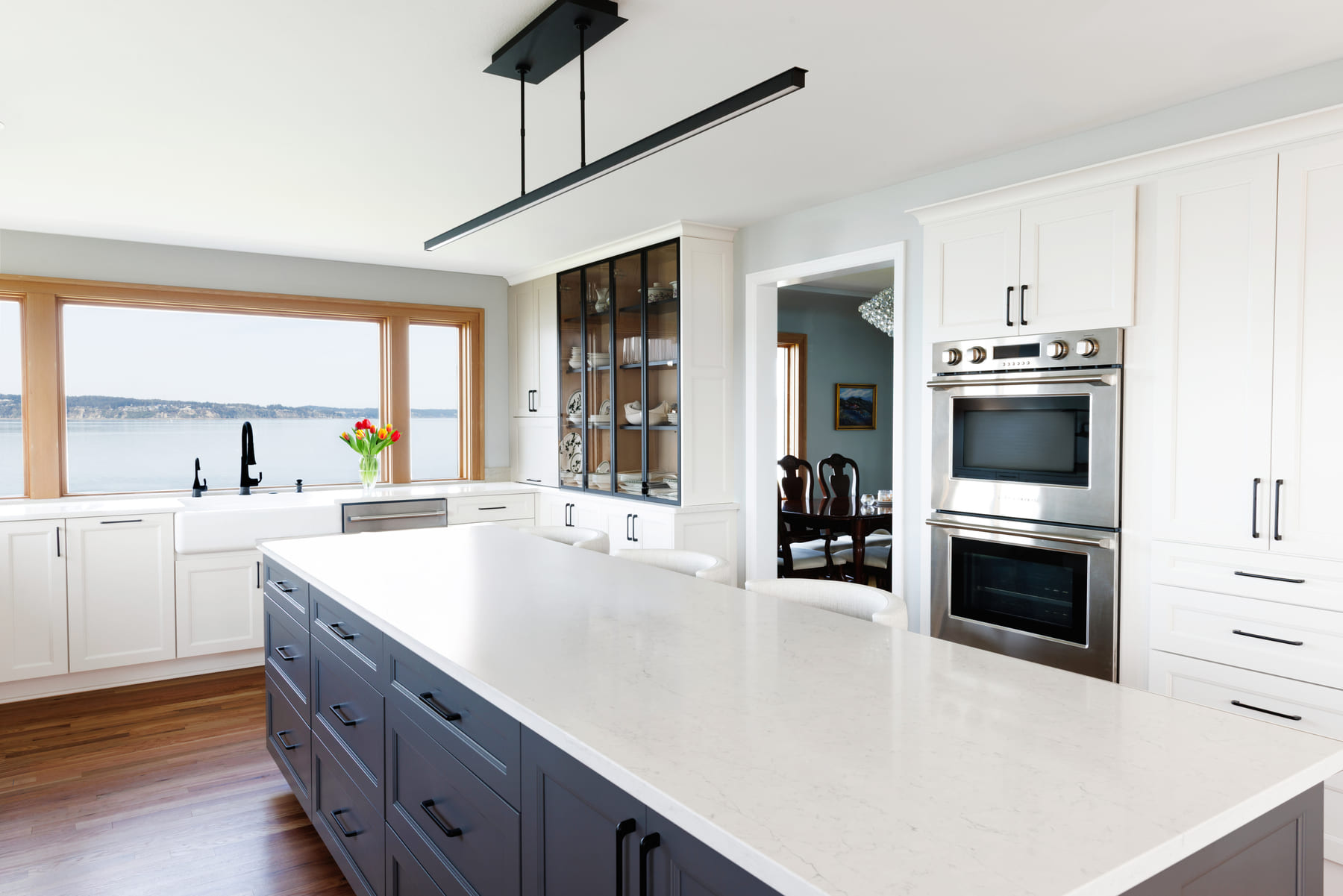 Modern kitchen in Steilacoom featuring large windows that showcase a stunning view, bringing natural light and scenic beauty into the space.